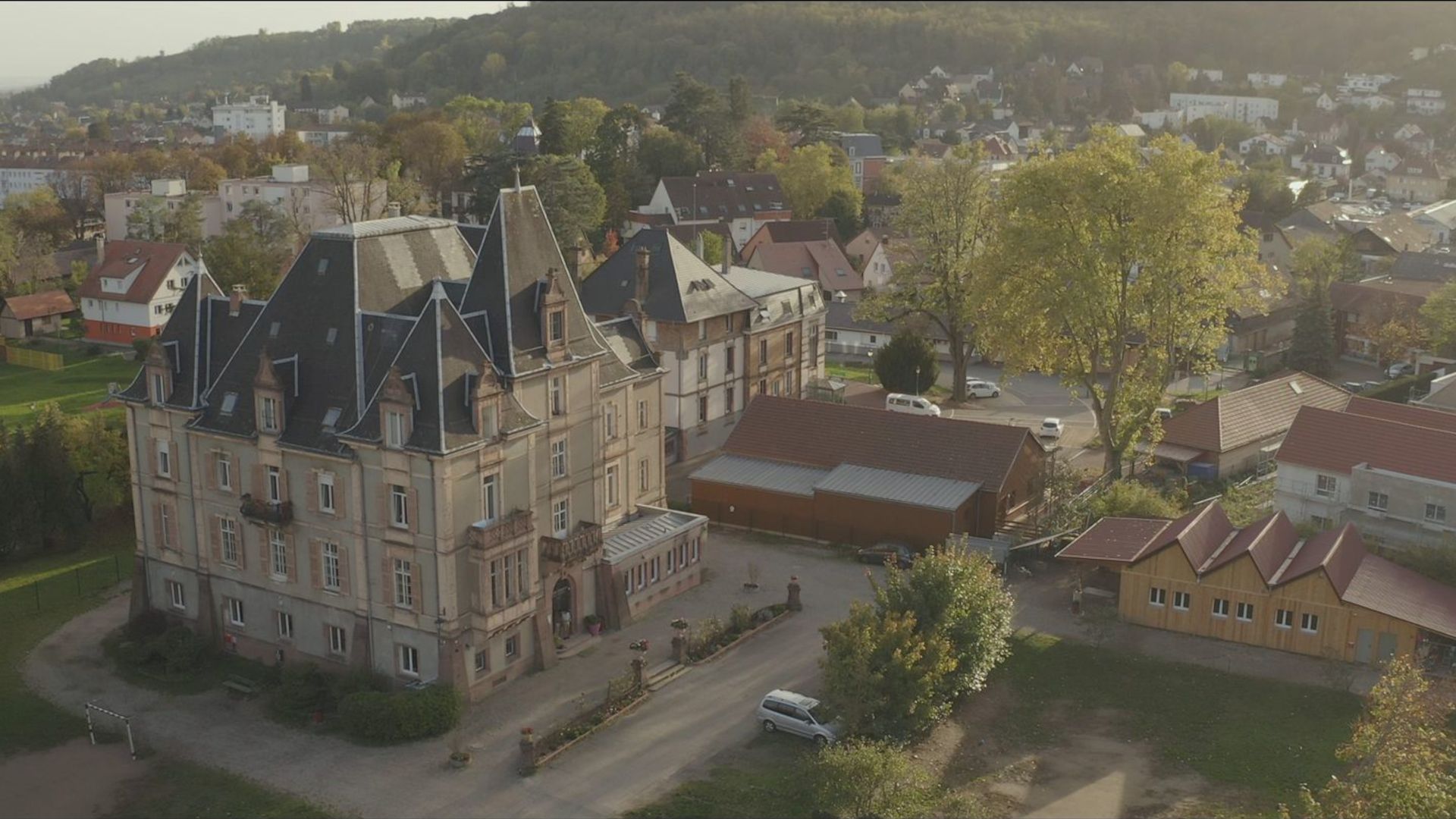 Vue aérienne d'une ville avec un château en arrière-plan, mettant en valeur l'architecture et le paysage environnant.